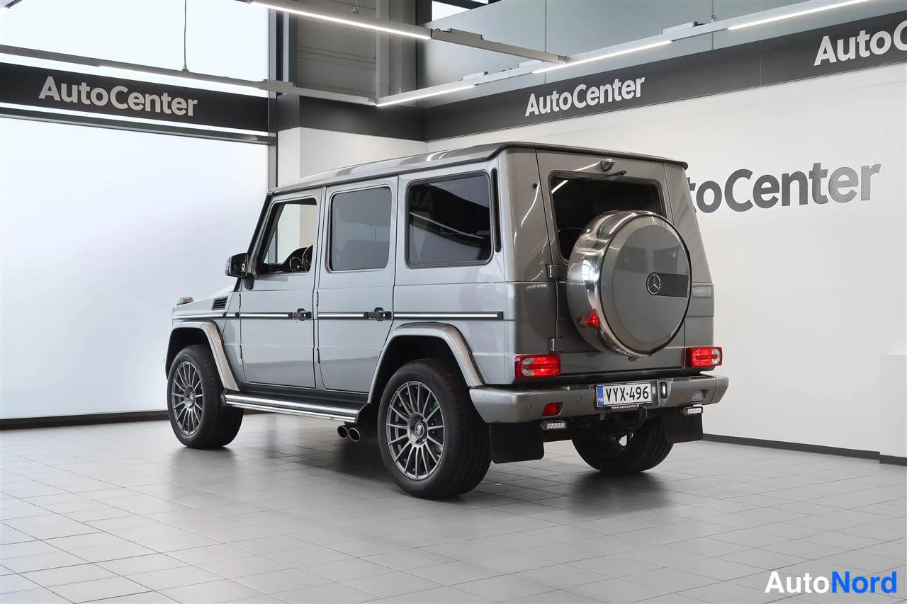 Takaviisto: Hopeanharmaa Mercedes-Benz G takaviistosta kuvattuna; rekisterikilpi, varapyörä kannella ja sivupeilit näkyvät.