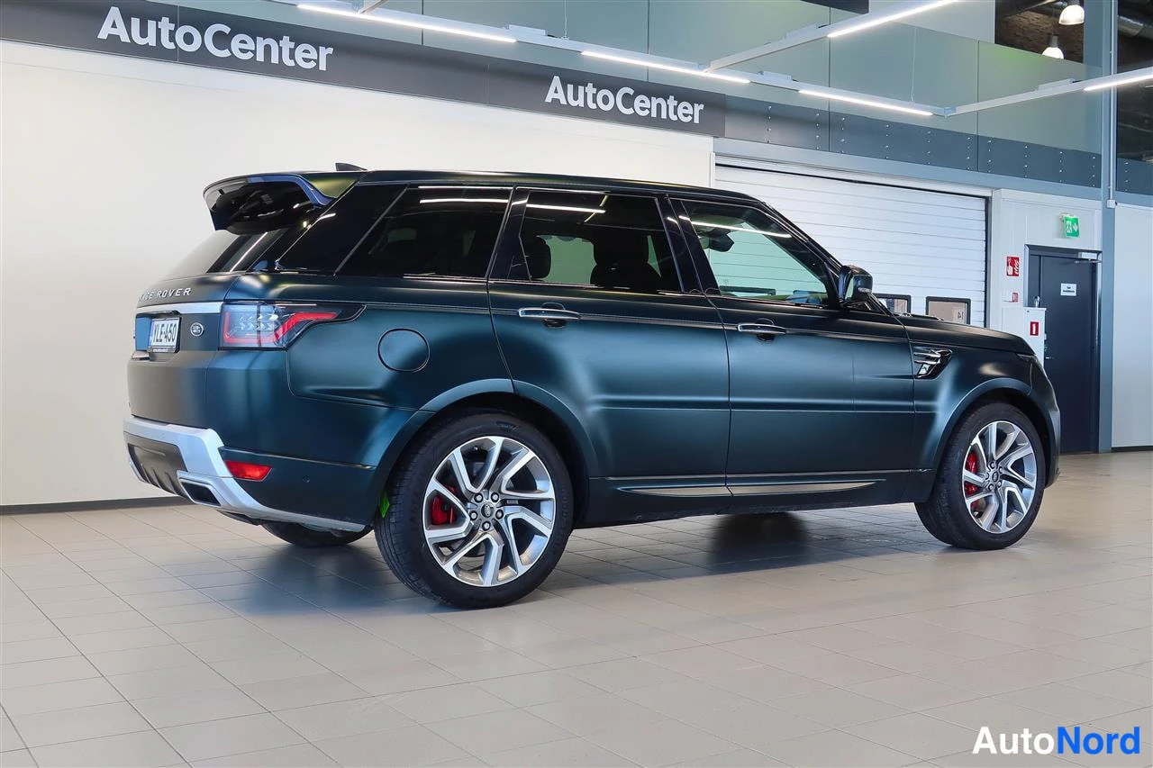 Takaviisto: Tummansinivihreä Land Rover Range Rover Sport takaa sivulta kuvattuna autonäyttelytilassa.