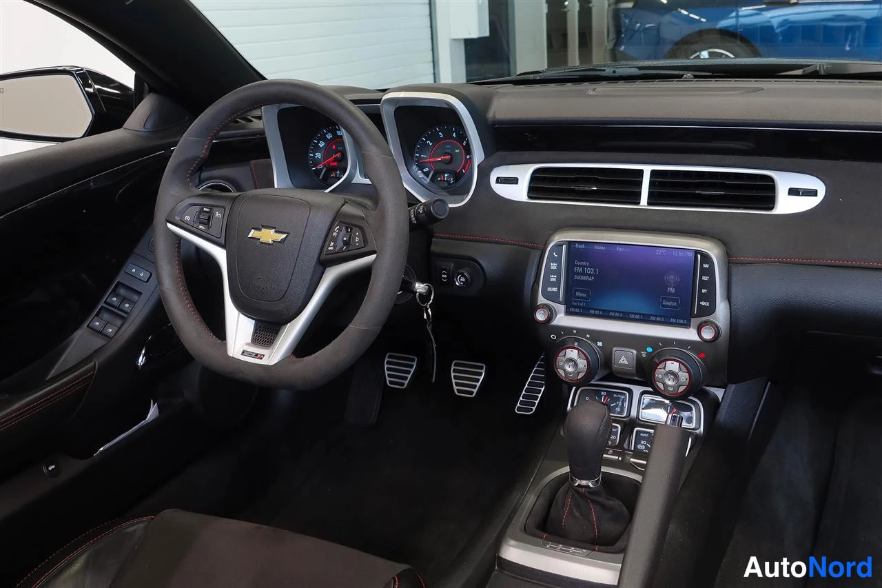 Muu: Camaro-ohjaamo kuljettajan puolelta: Chevrolet-merkkinen ohjauspyörä, analogiset mittarit, kosketusnäytön radio ja manuaalienvaihtaja.