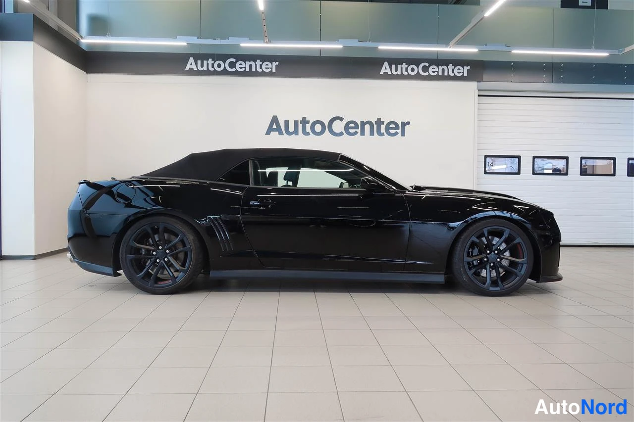 Sivulta: Mustan avoimiauton sivukuva, katto ylhäällä, AutoCenter-hallissa.