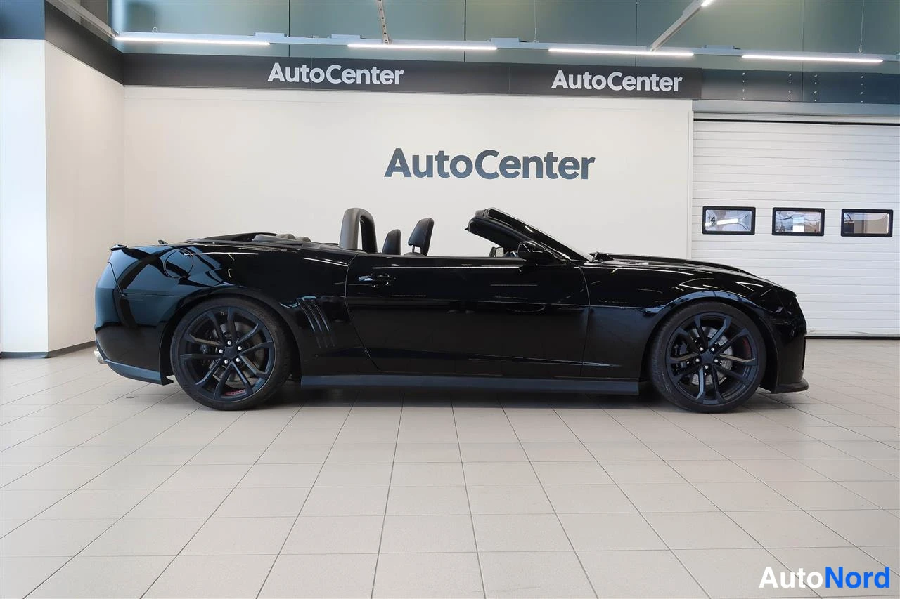 Sivulta: Mustan avoimiauton sivukuva, katto auki, AutoCenter-hallissa.