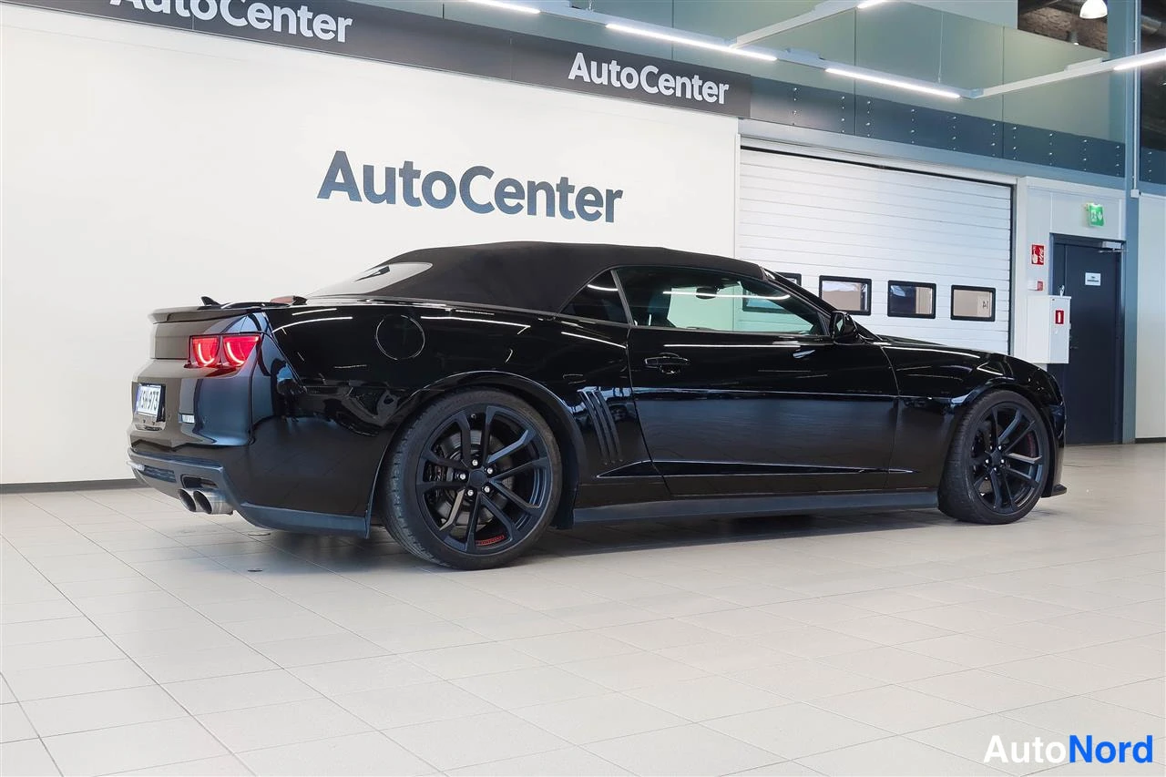 Takaviisto: Mustan avoimiauton takaocolma-kulma, katto ylhäällä, AutoCenter-hallissa.