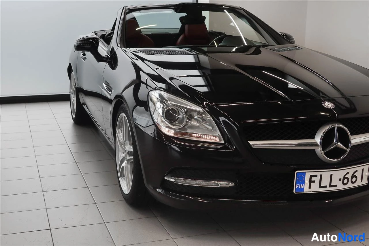 Etuviisto, nokka oikealle: Mustan Mercedes-Benz SLK:n etupää lähikuvassa, etusuoja ja kylki näkyvissä, rekisteritunnus.