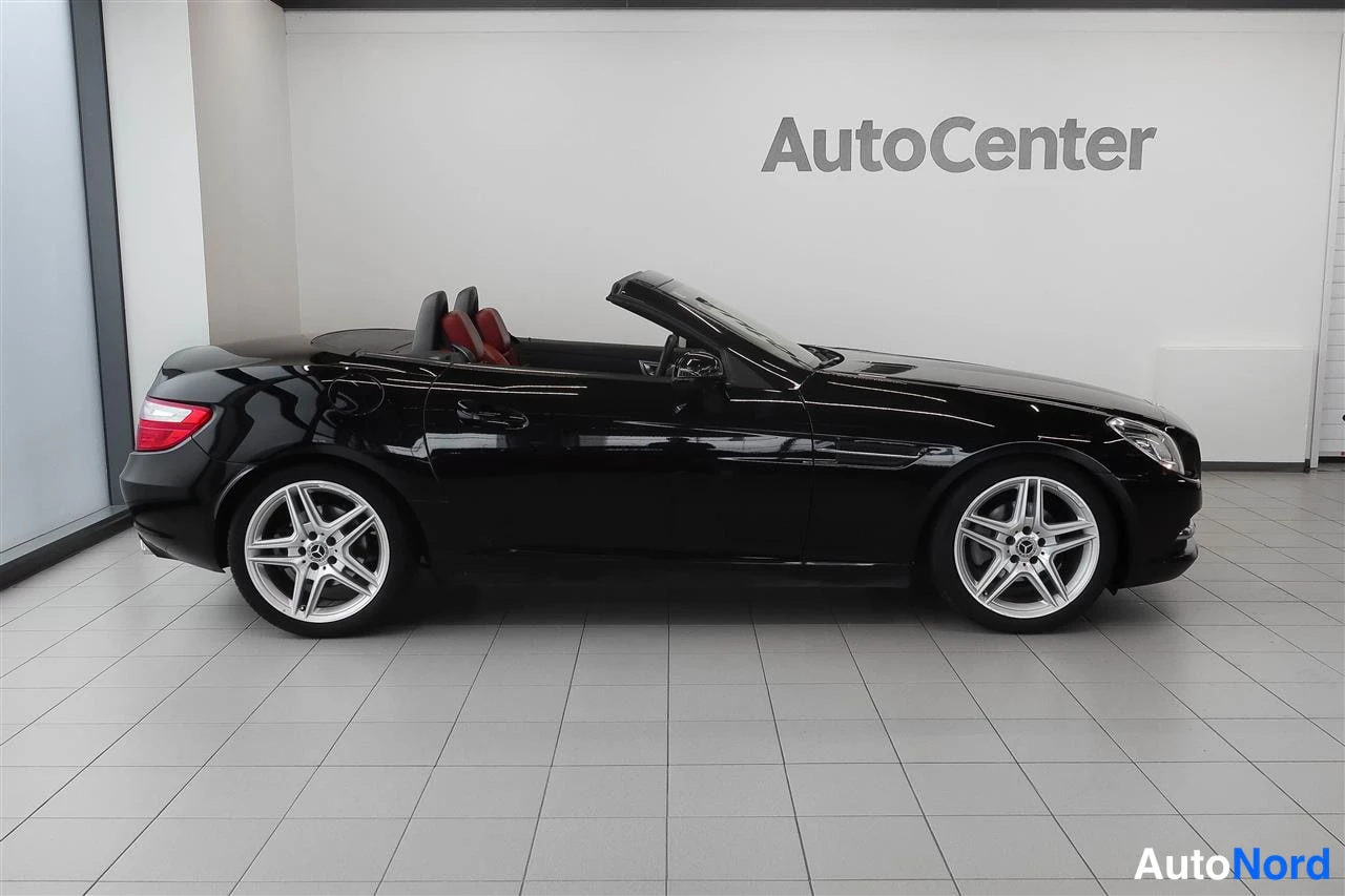 Takaviisto: Musta avomeren Mercedes-Benz SLK sivulta, takavalo näkyvissä, kangaskatto auki.