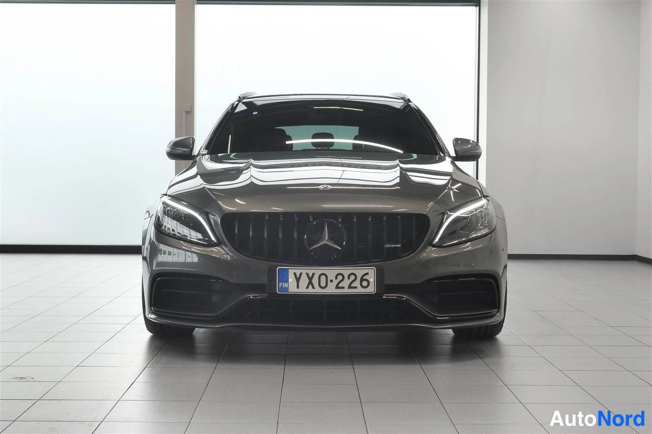 Edestä: Tummanharmaan Mercedes-Benz farmarin suora etunäkymä, paneelikyltti, AutoCenter-tila.
