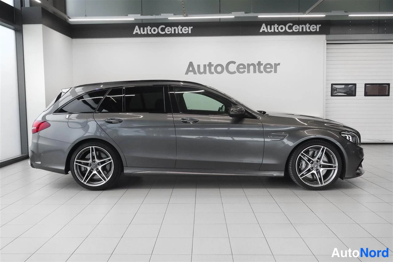 Sivulta: Tummanharmaan Mercedes-Benz farmarin sivunäkymä vasemmalta, AutoCenter-tilassa.