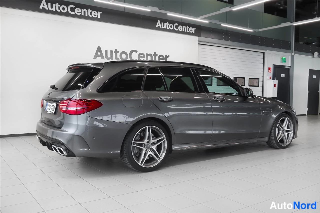 Takaviisto: Auton takaosa ja oikea sivu kolmen neljäsosan kulmasta, tummanharmaa farmarimalli AutoCenter-hallissa.