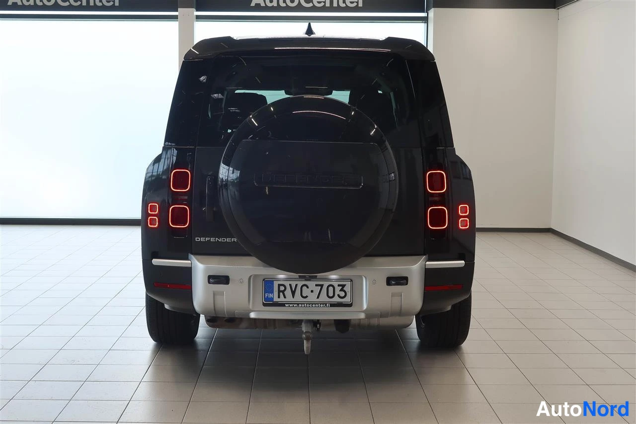 Takaa: Land Rover Defenderin suora takanäkymä: DEFENDER-teksti, pyöreät takavalot ja rekisteritunnus.