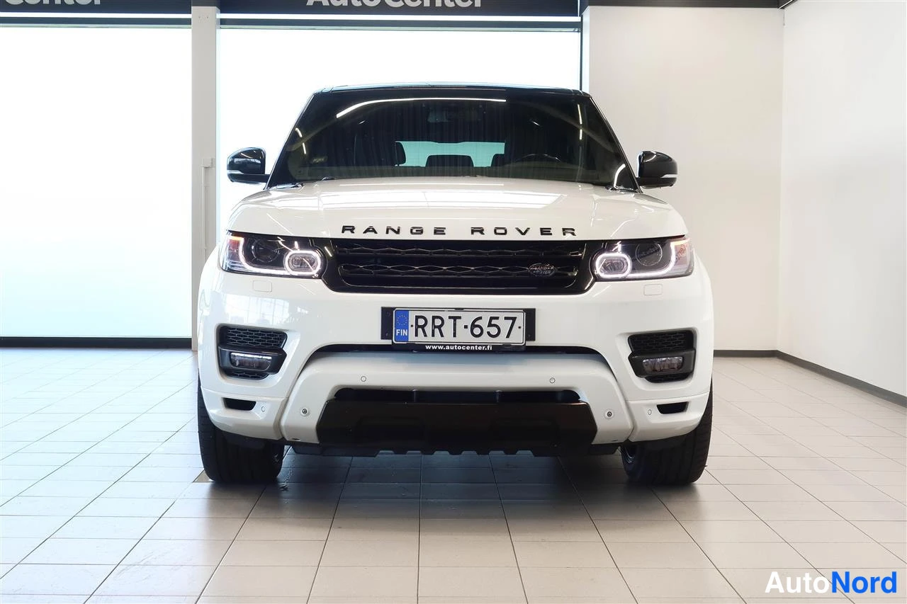 Edestä: Valkoisen Land Rover Range Rover Sportin etupää, rekisterikilpi ja Range Rover -teksti konepellissä.
