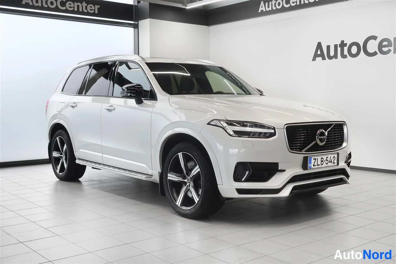 Etuviisto, nokka oikealle: Valkoinen Volvo XC90 etuosa kolmesta neljännekseen näytöllä, mustat kevytmetallivanteet