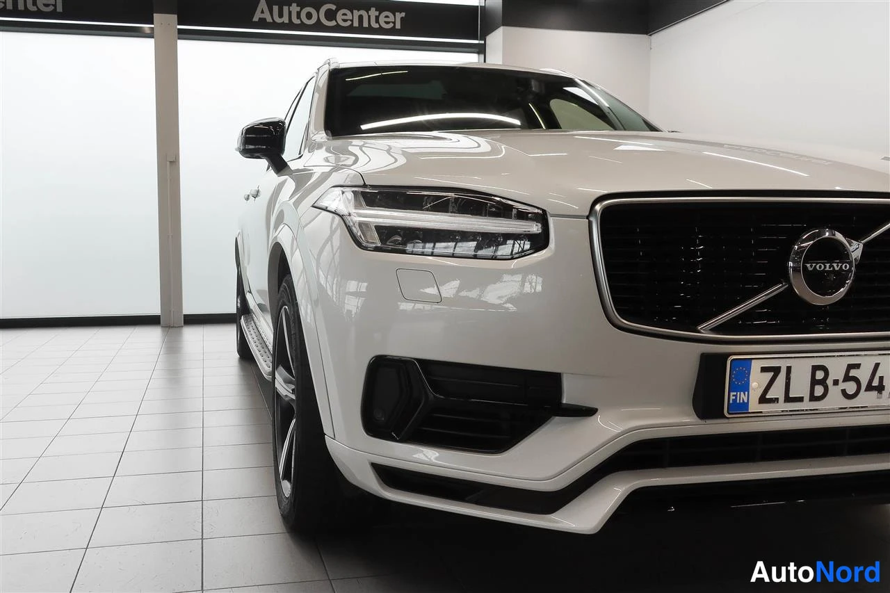 Etuviisto, nokka oikealle: Valkoisen Volvon XC90 etusäleikkö ja ajovalot lähikuvassa, rekisteritunnus