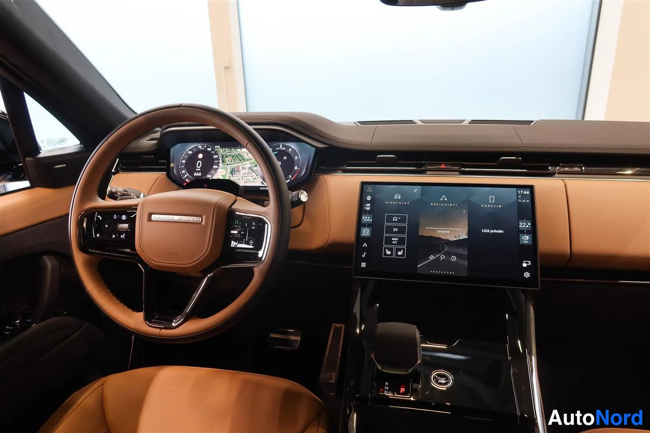 Muu: Ohjaamo suoraan edestä: tan-nahkainen ohjauspyörä 'RANGE ROVER' -tekstillä, digitaalinen mittaristo ja keskitörmäsuuri kosketusnäyttö.