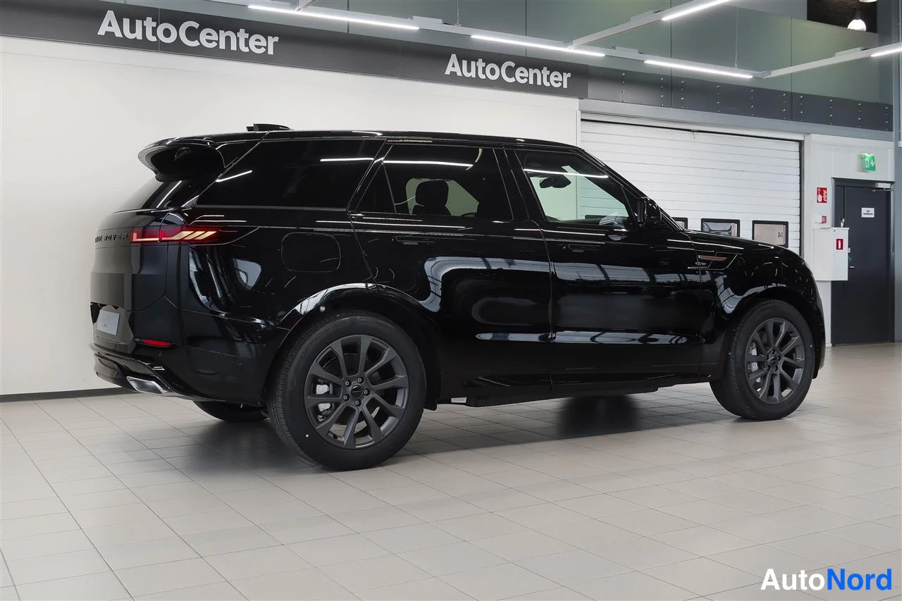 Takaviisto: Mustan Range Rover Sportin takakulmanäkymä sisätiloissa, taivalta ja kylki näkyvät, tummat kevytmetallivanteet.