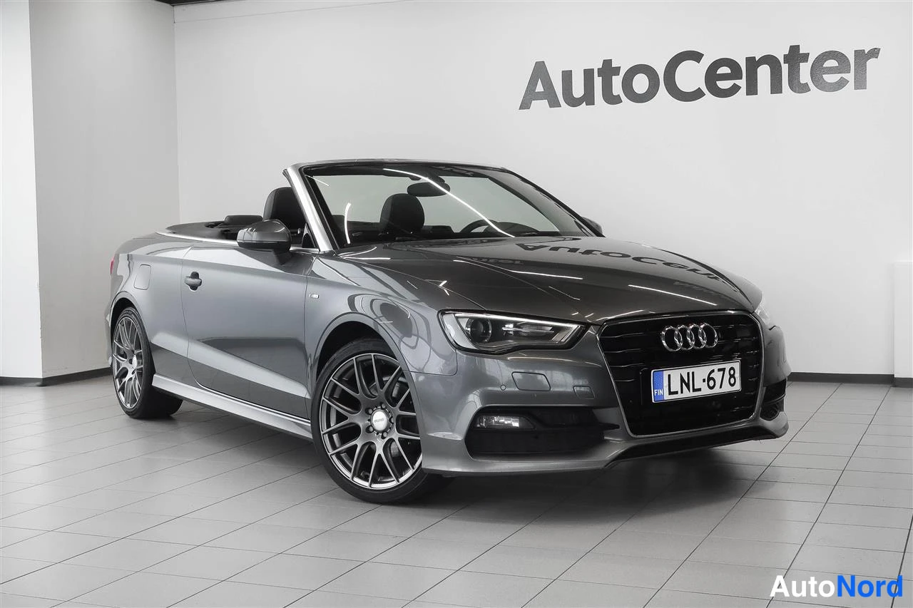 Etuviisto, nokka oikealle: Harmaa Audi A3 Cabriolet etukolmionäkyvällä, katto auki, rekisterikilpi