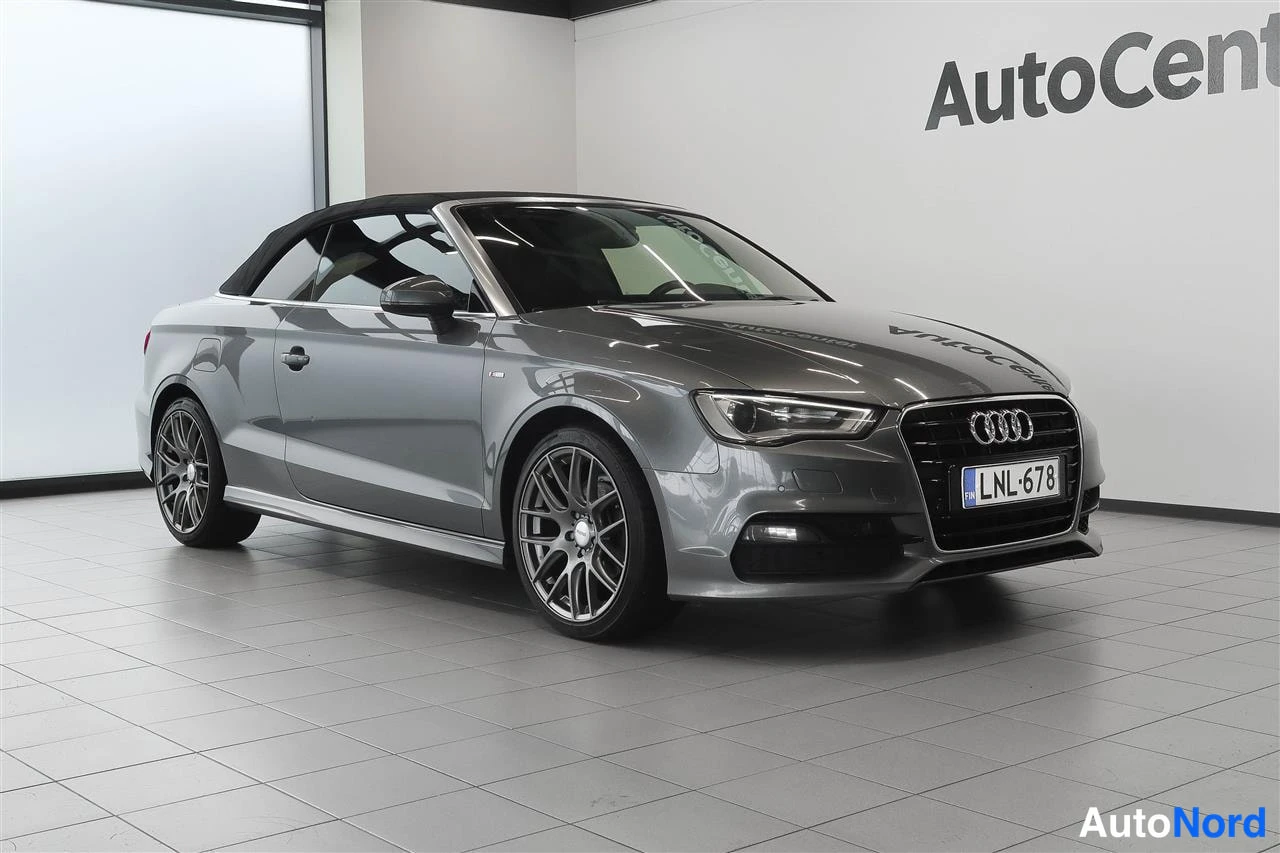 Etuviisto, nokka oikealle: Harmaa Audi A3 Cabriolet etukolmionäkyvällä vasemmalta, katto ylhäällä