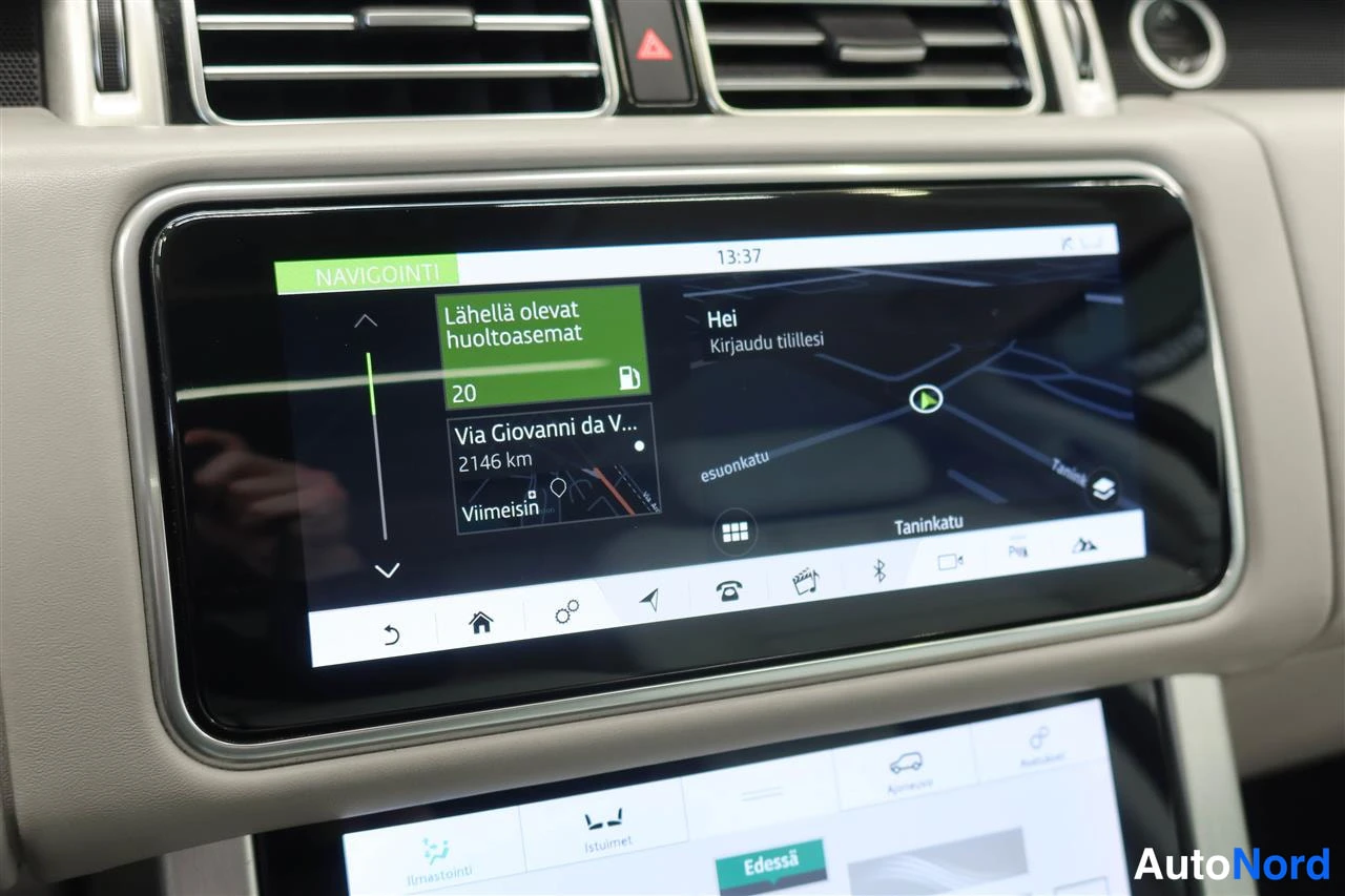 Yksityiskohta: Auton infotainment-näyttö NAVIGOINTI-näkymässä: lähellä olevat huoltoasemat ja kartta, kellonaika 13:37.