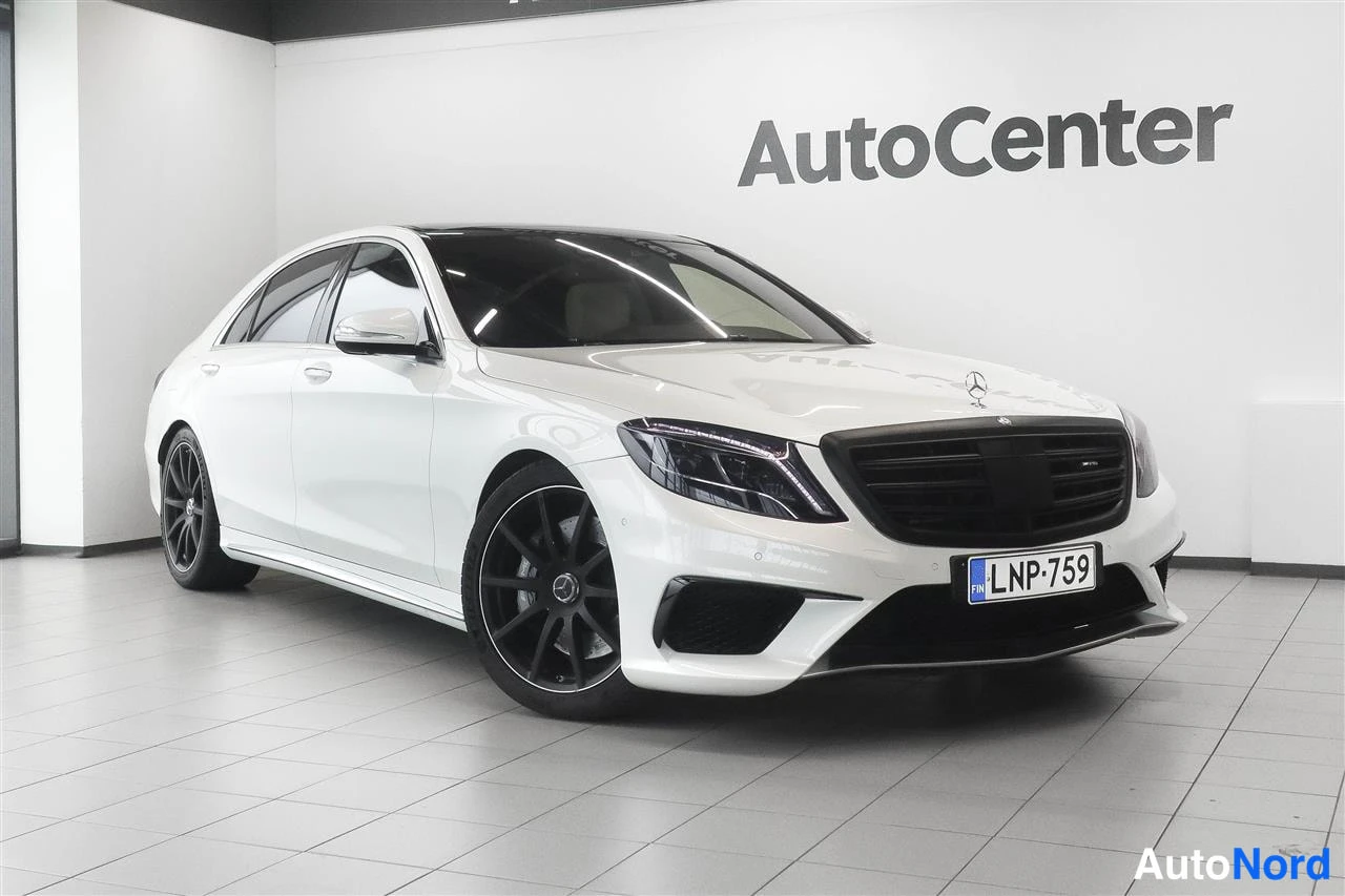 Etuviisto, nokka oikealle: Valkoinen Mercedes-Benz S-luokan sedan edestä vasemmalta kuvattuna sisätiloissa, rekisteritunnus.
