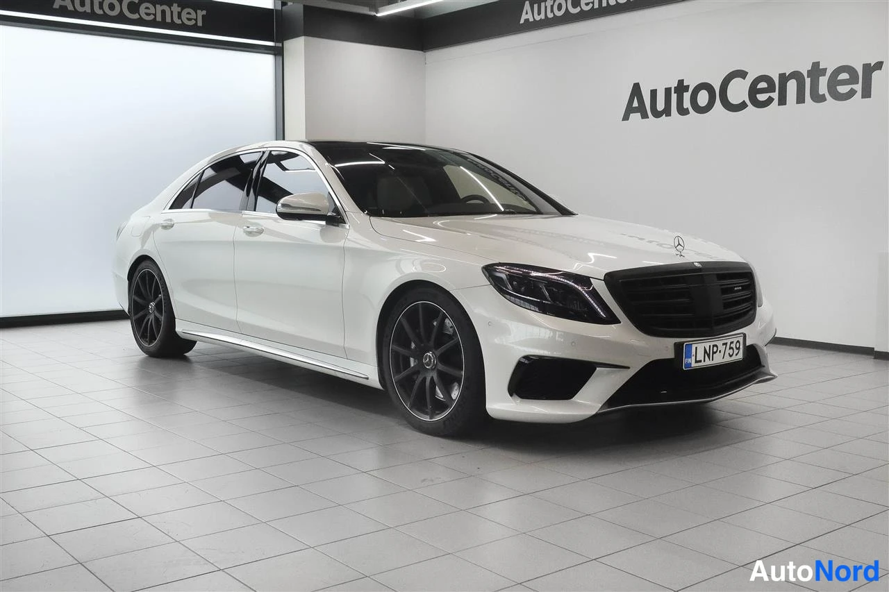 Etuviisto, nokka oikealle: Valkoinen Mercedes-Benz S-luokan sedan sisätiloissa, kuvattu edestä vasemmalta puolen, rekisteritunnus.