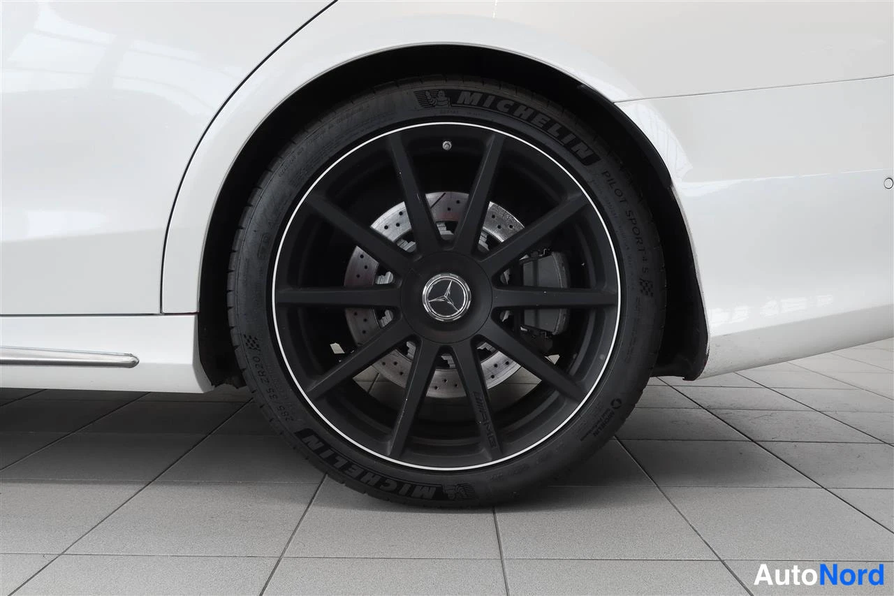 Sivulta: Musta kevytmetallivanne ja Michelin-renkuin varustettu pyörä valkoisessa Mercedes-Benzissä.