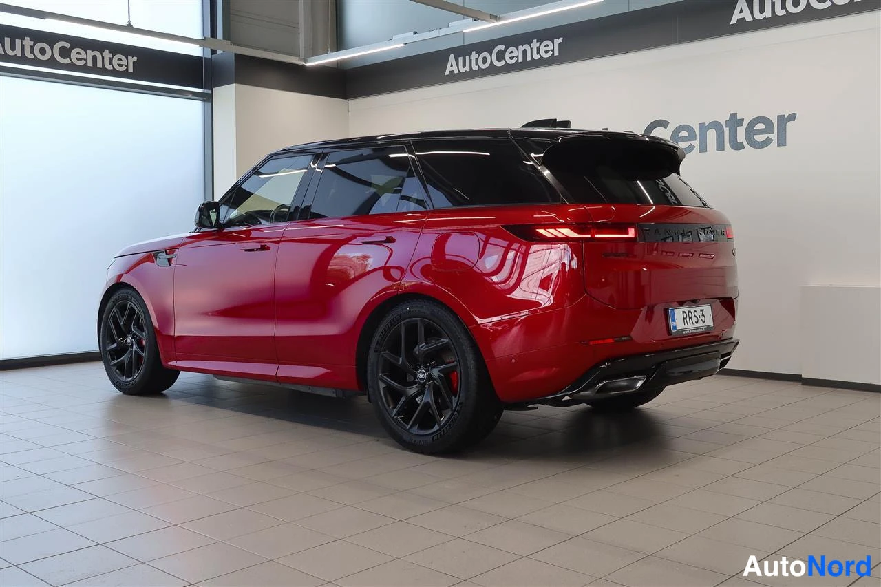 Takaviisto: Punainen Land Rover Range Rover Sport takana sivulta kuvattuna myymälässä; rekisterikilpi, mustat vanteet ja takavalot näkyvät.