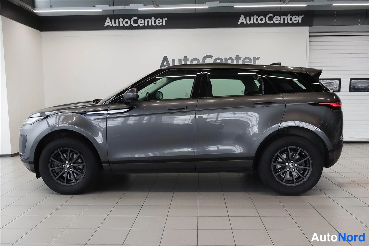 Sivulta: Land Rover Range Rover Evoquen sivuprofiili; tummanharmaa kori, mustat kevytmetallivanteet ja tummat ikkunakehykset showroomissa.