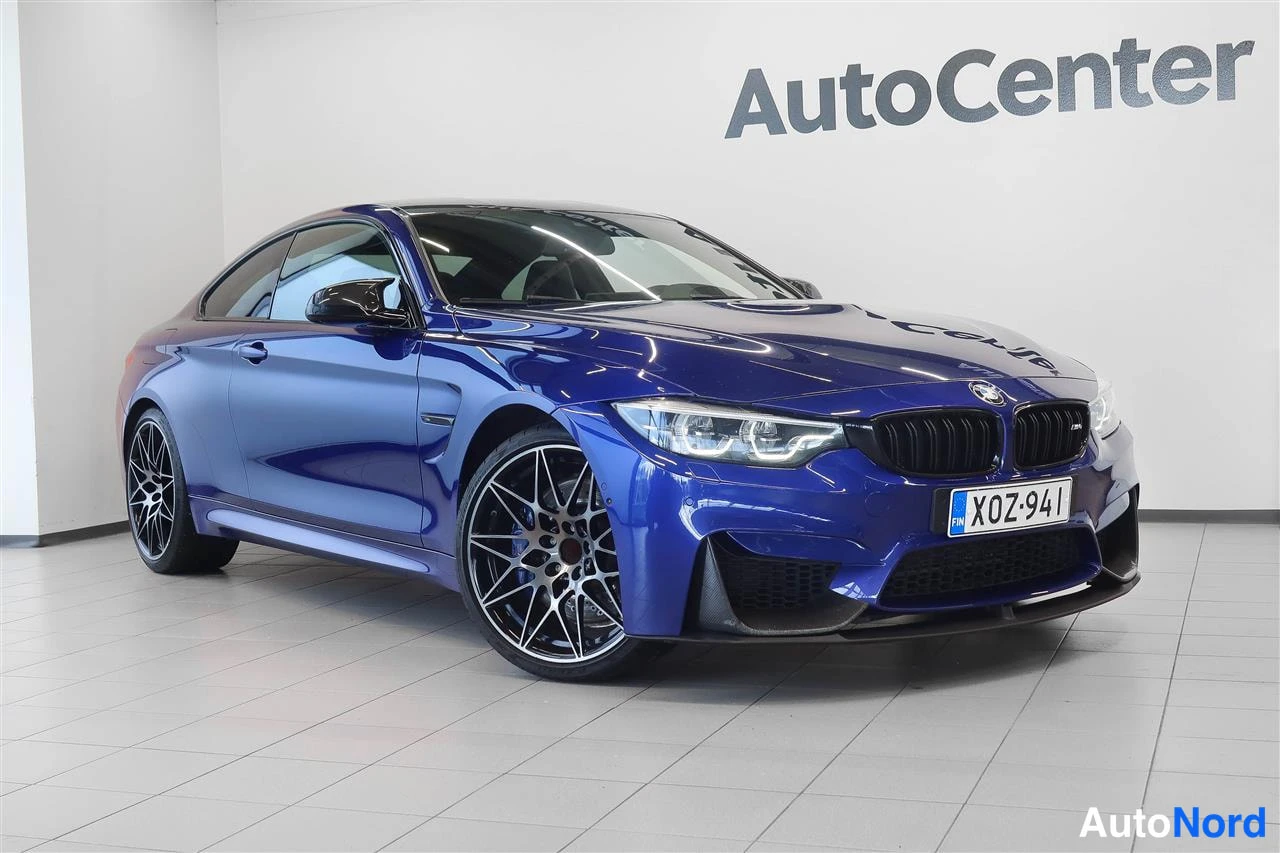 Etuviisto, nokka oikealle: Sininen BMW M4 -urheilucoupé näkyy etu-kolmasosan kuvassa sisätiloissa, maski ja etupyörä näkyvät.