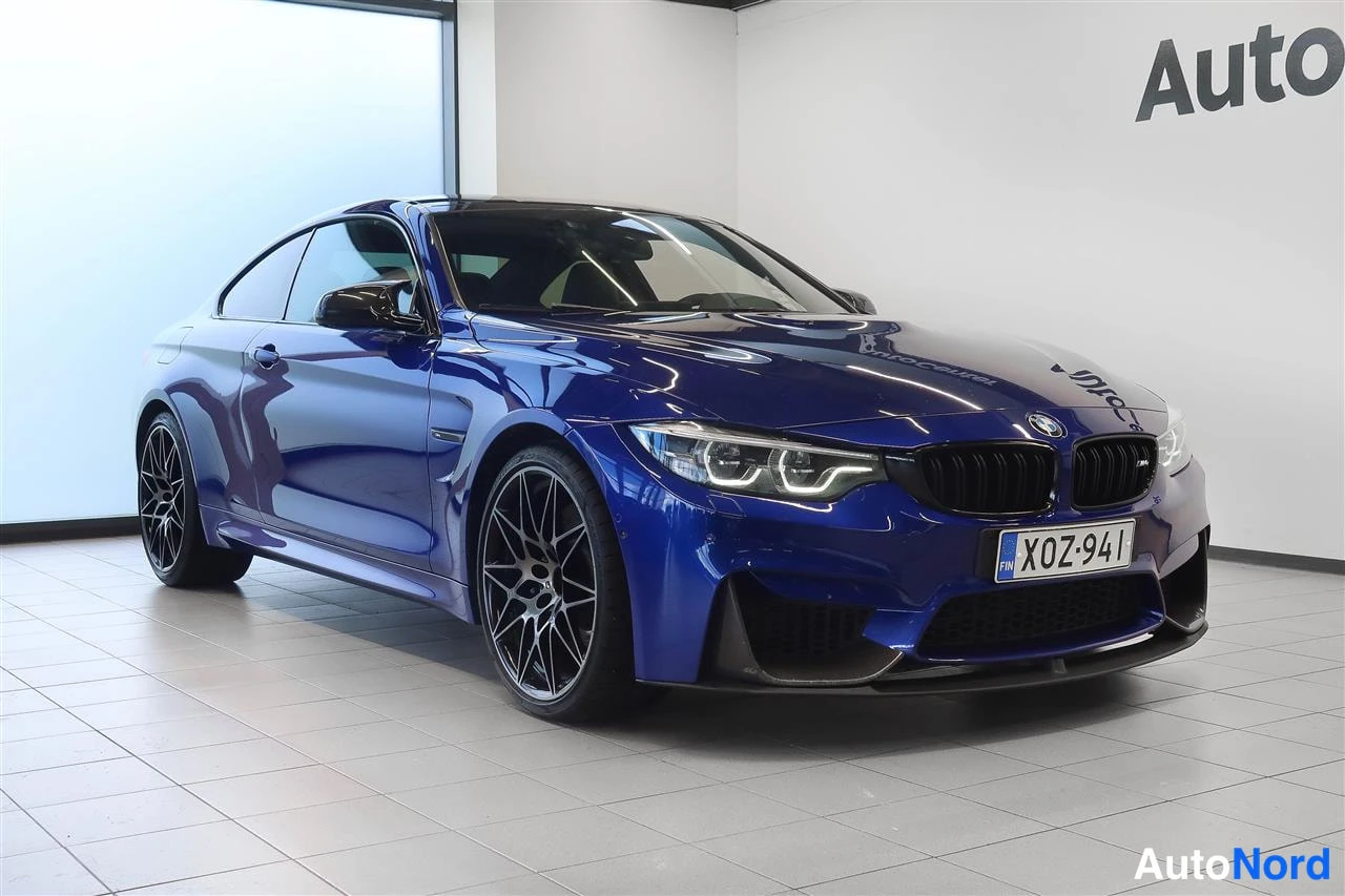 Etuviisto, nokka oikealle: Sininen BMW-coupé etu-kolmasosakuvassa autohallissa, keulamaski ja rekisterikilpi näkyvät.