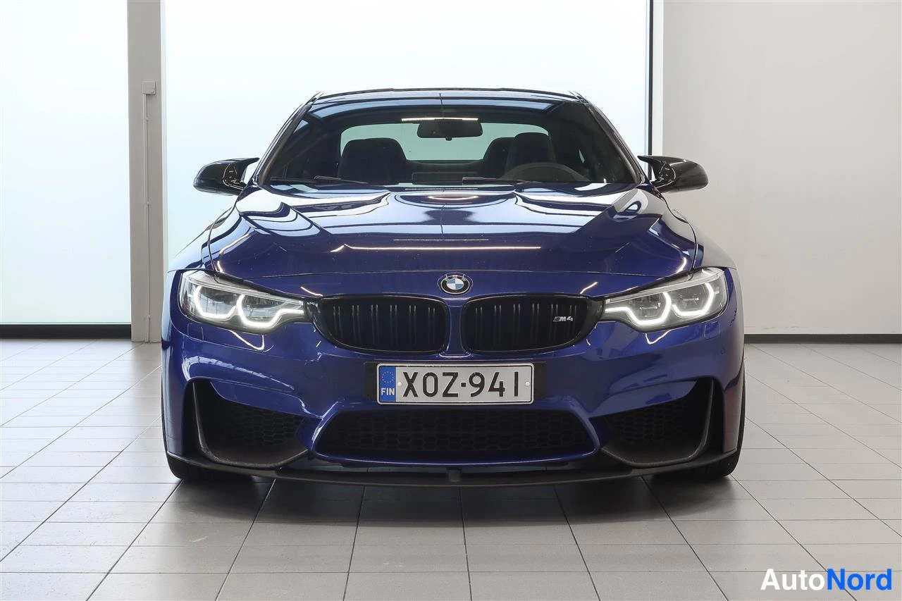Edestä: Sinisen BMW-auton keulakuva edestä päin, maski, LED-ajovalot ja rekisterikilpi näkyvät.