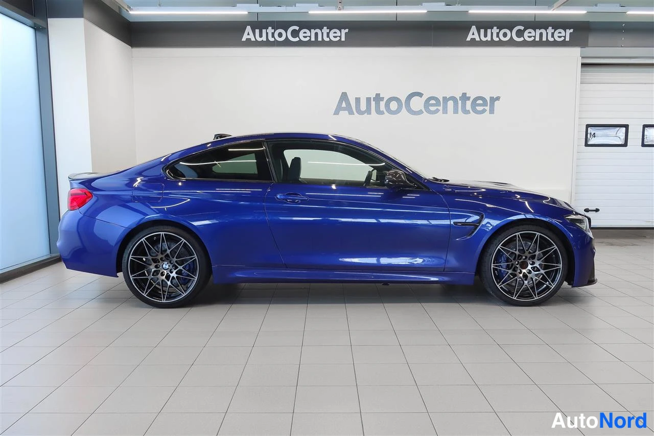 Sivulta: Sininen BMW M4 -coupé sivusta kuvattuna autotallissa.