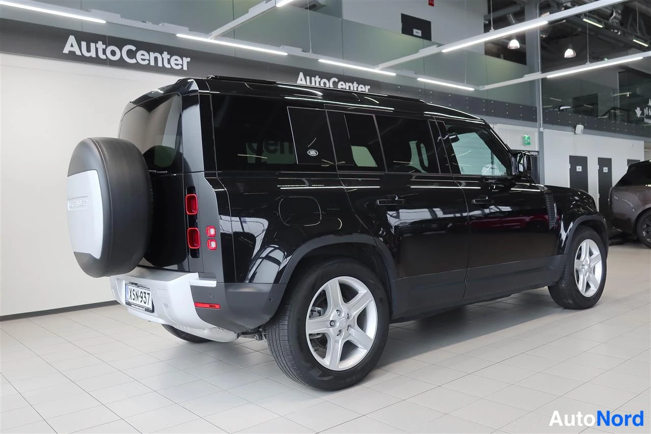 Takaviisto: Land Rover Defender takaa viistosti vasemmalta, vara pyörä tavaratilan kannessa.