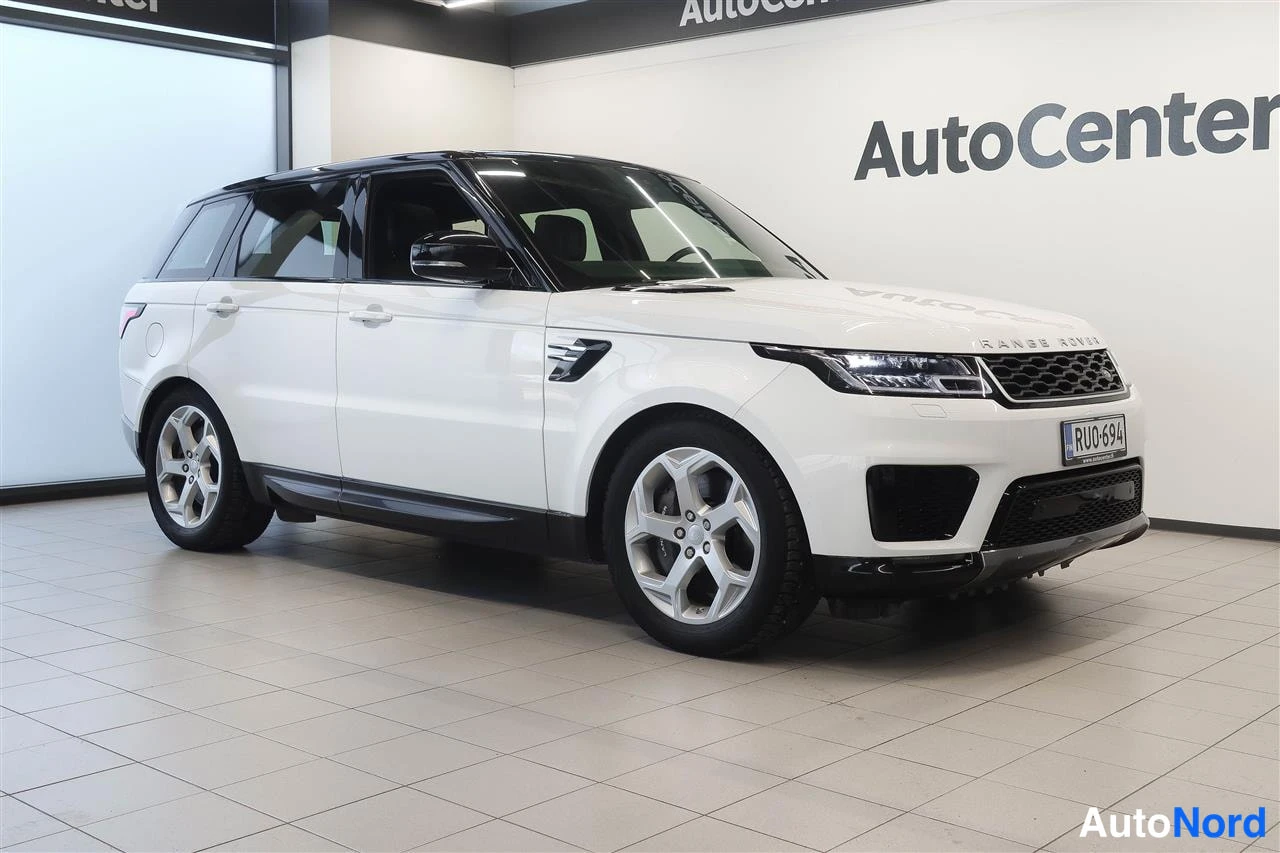 Etuviisto, nokka oikealle: Valkoinen Range Rover Sport etukulmasta oikealta sisätiloissa, musta katto, rekisteri.