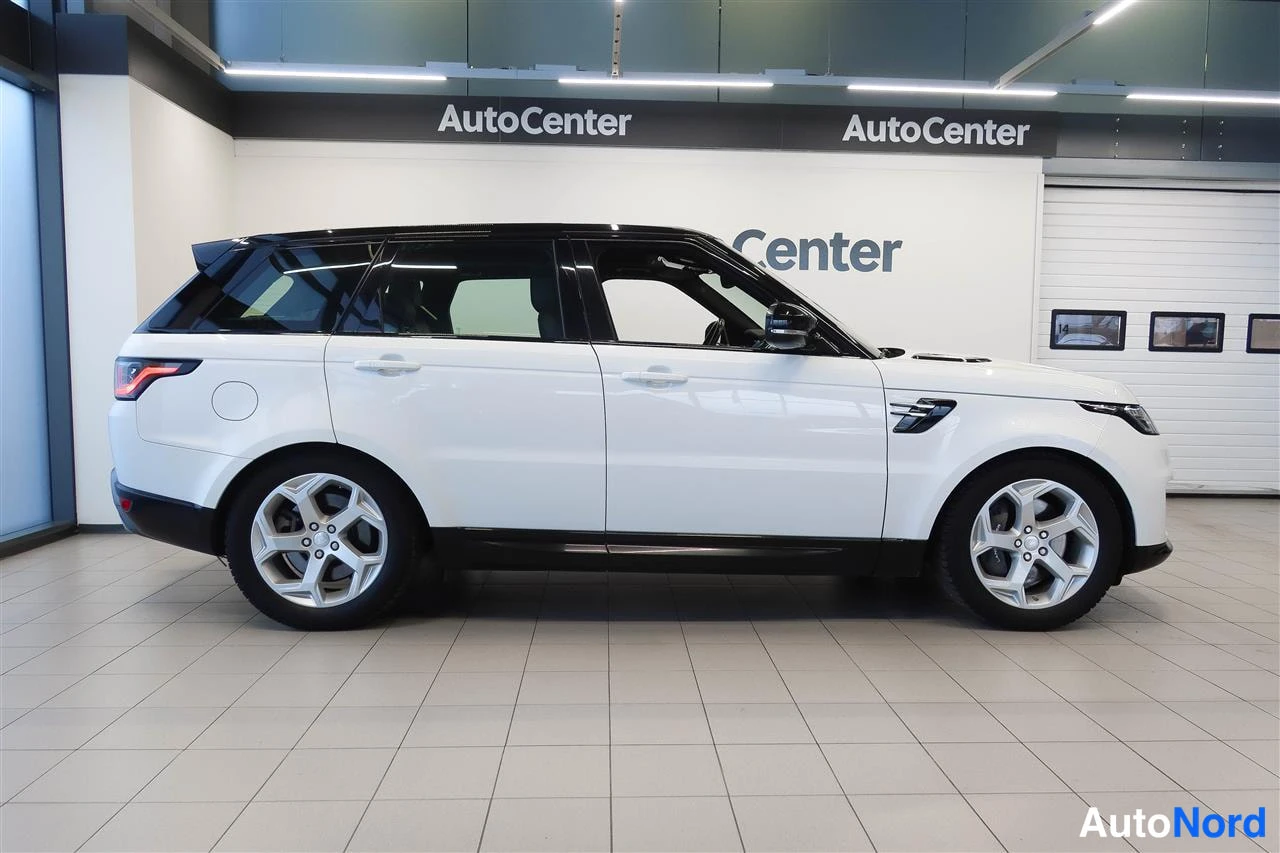 Sivulta: Valkoisen Range Rover Sportin sivunäkymä oikealta, musta katti, hopeat vanteet, takavalot osin näkyvissä.