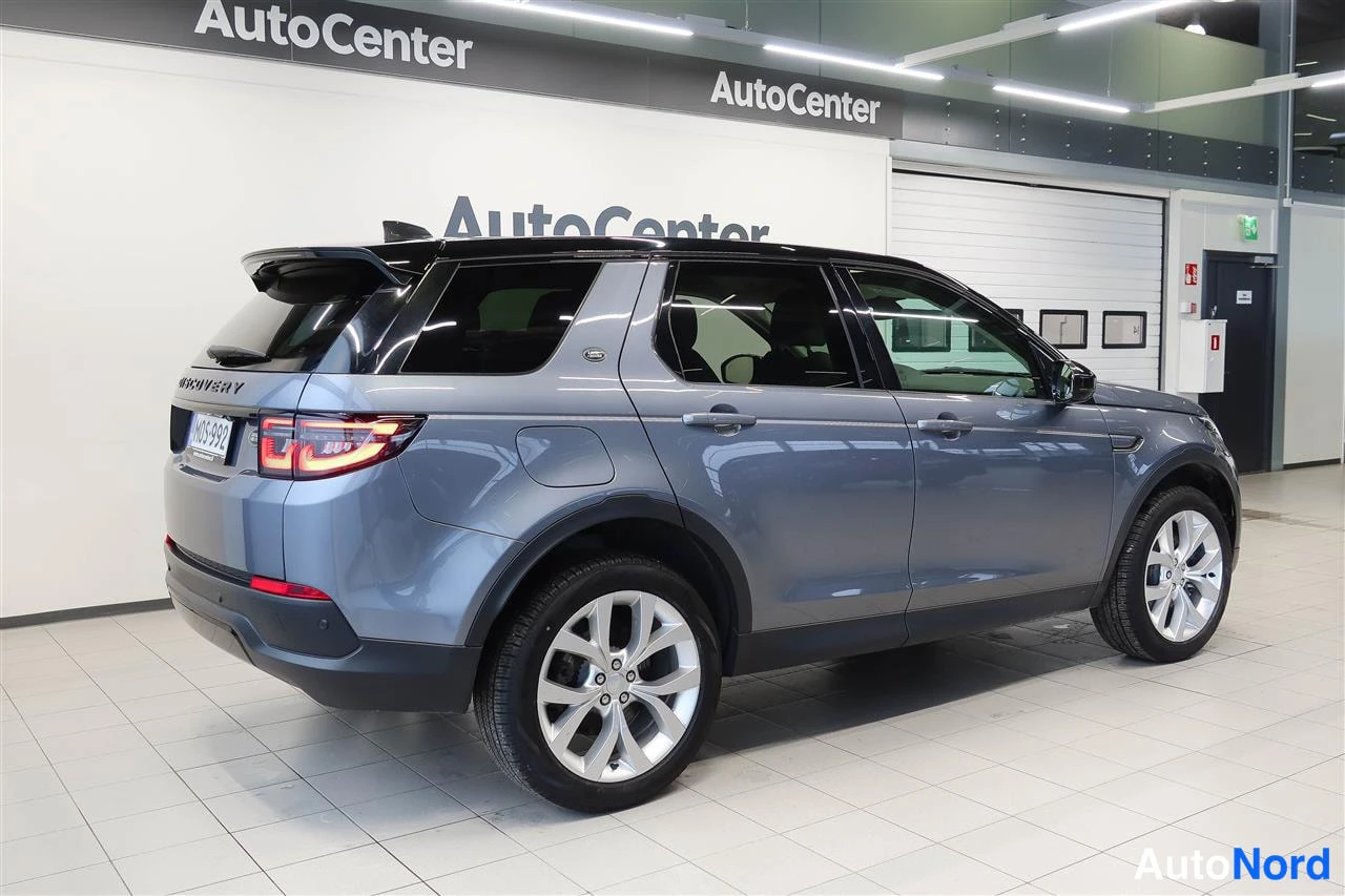 Takaviisto: Land Rover Discovery Sportin takakulma vasemmalta, harmaa kori, takavalot ja -kilpi näkyvissä.