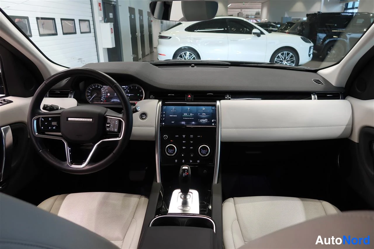 Muu: Land Rover Discovery Sportin ohjaamo etupäältä: monitoimiohjauspyörä, digitaalinen mittaristo, keskellä kosketusnäyttö ja automaattivaihteen valitsin.