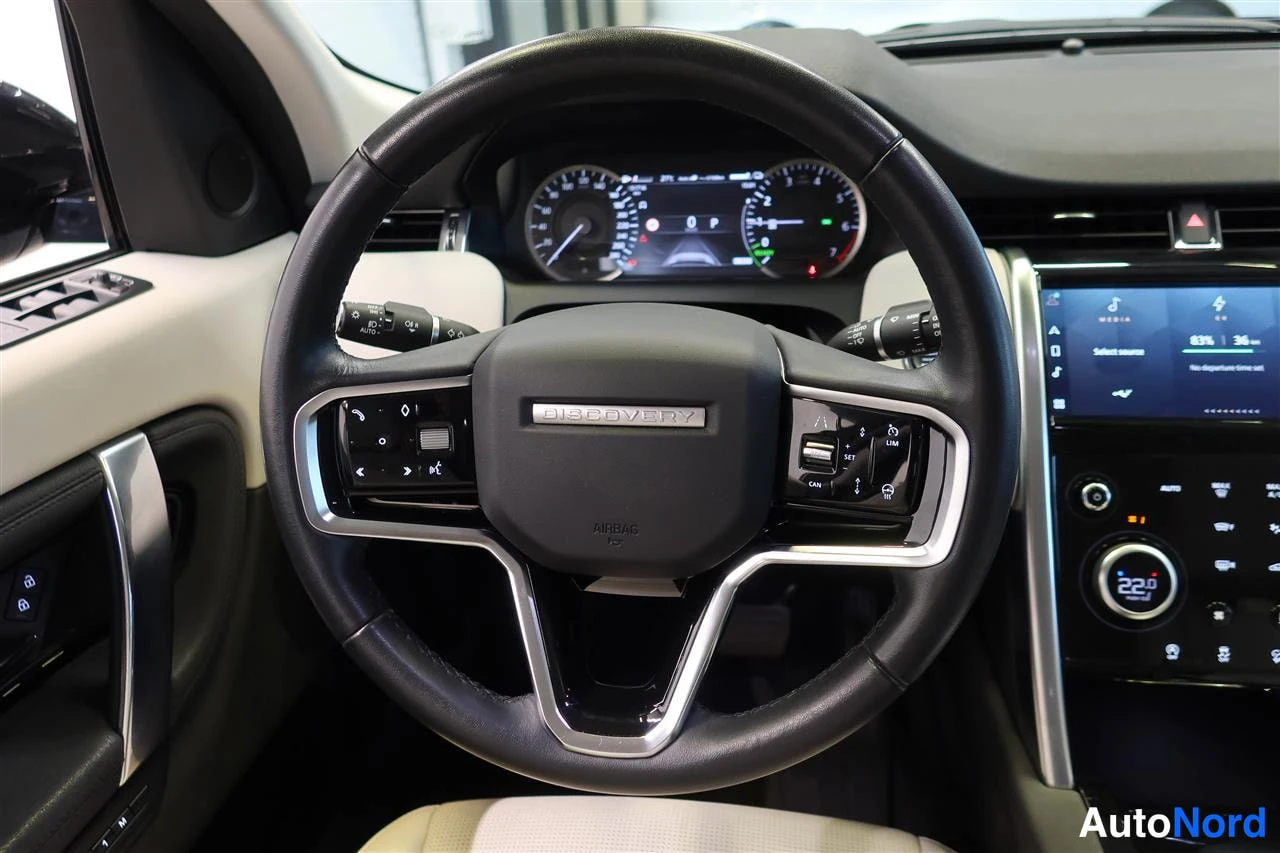 Muu: Land Rover Discovery Sportin ohjauspyörän lähikuva: DISCOVERY-merkitty ohjauspyörä, ilmatyynymerkintä, digitaalinen mittaristo ja multimediatäyttö näkyvät.