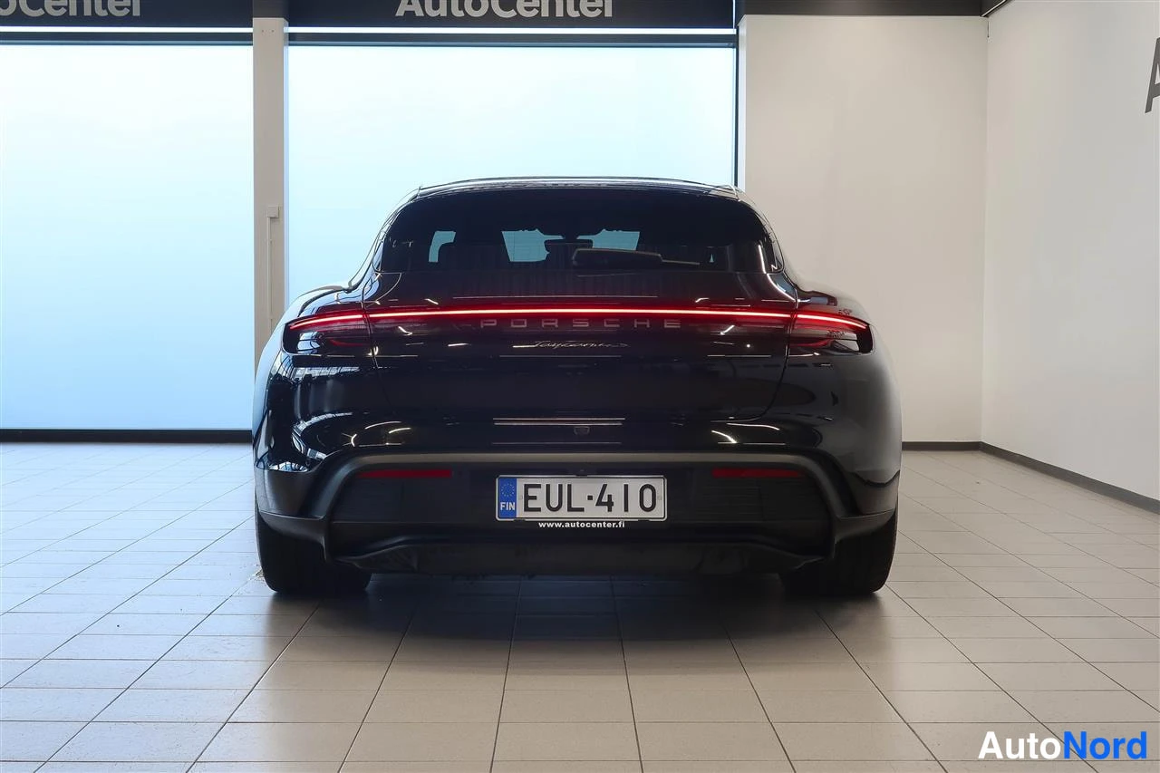 Takaa: Mustan automobiilin takaosa suoraan takaa valaistuna; punainen takavalonpoikki, PORSCHE-takamerkinnät ja rekisterikilpi näkyvät.