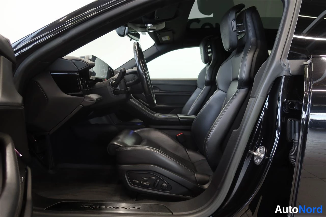 Muu: Sisätilakuva Porsche Taycanista: musta ohjaamo, urheiluistuimet, ohjauspyörä ja otsikko-Taycan 4S-kynnyuskoriste.