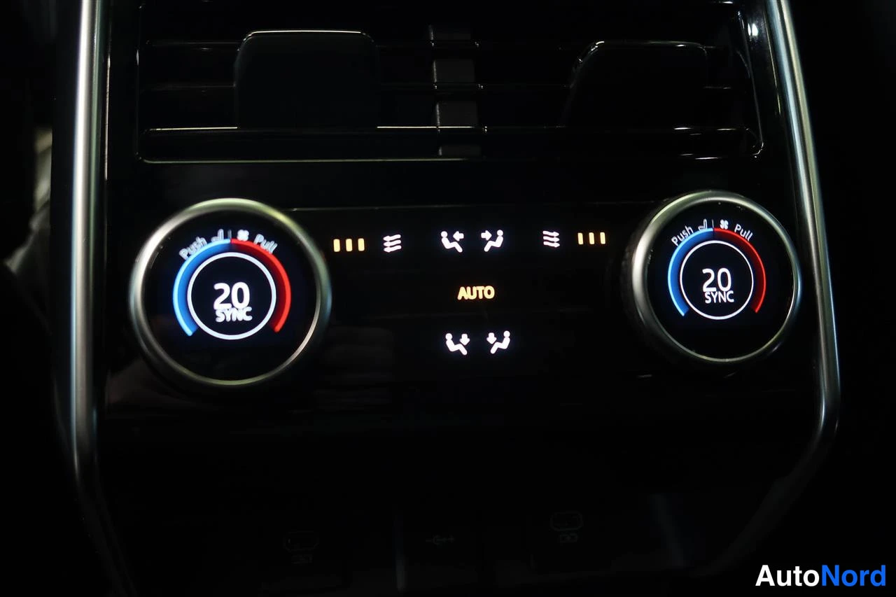 Muu: Takin lämmityksen hallintapaneeli kahdella kierrätysnupilla, molemmissa asetus 20 ja SYNC-teksti, keskellä AUTO-merkintä.