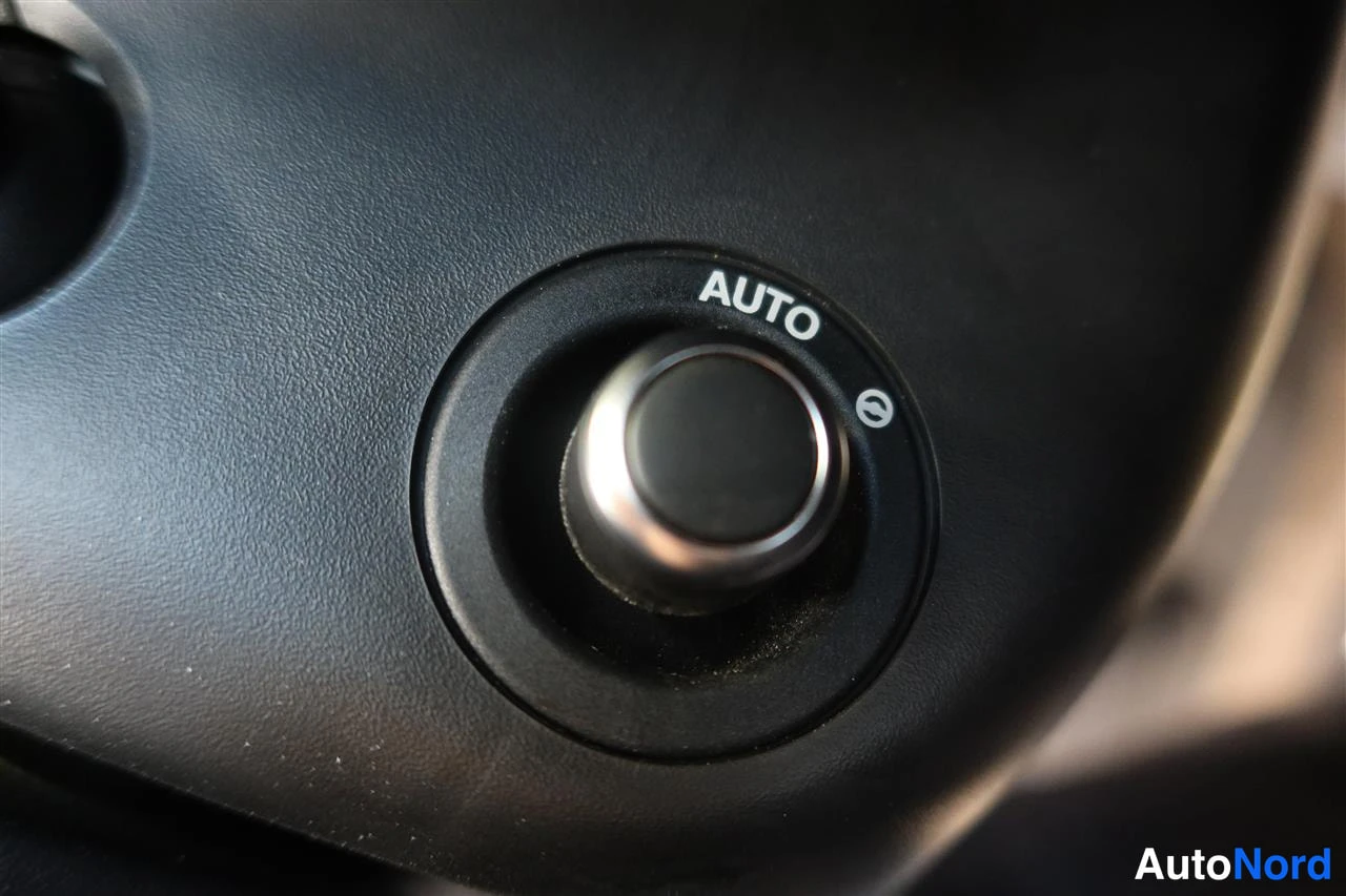 Yksityiskohta: Sisätilan lähikuva tummasta pyörivästä säädinnupista, jonka vieressä lukee AUTO.