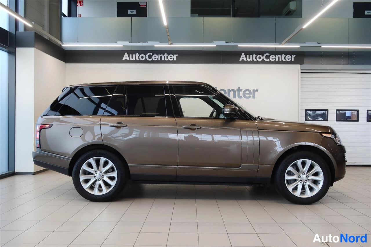 Etuviisto, nokka oikealle: Ruskeanmetallinhohtoinen Land Rover Range Rover autonäyttelyn lattiassa, etukulmastikuvassa keulalla oikealle.