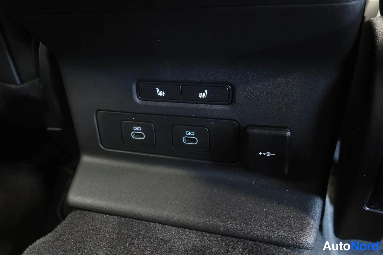 Edestä: Takaistuimen takapuolen paneeli, kaksi USB-C-porttia, istuinlämmityskytkimet ja 12V-pistorasiakytkin.