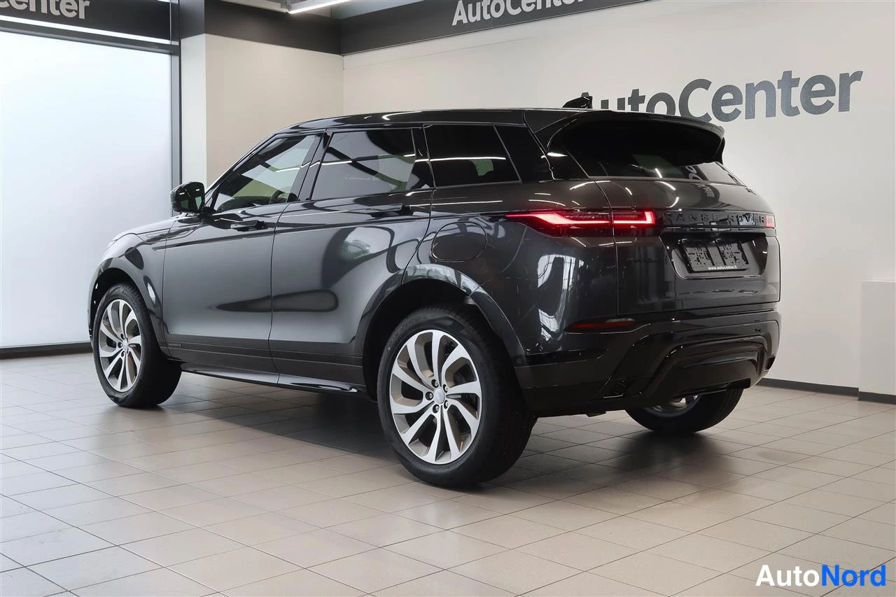 Takaviisto: Tummanharmaan Land Rover Range Rover Evoquen takakulma, takavalo ja rekisterikilpi näkyvät autonäyttelyhallissa.