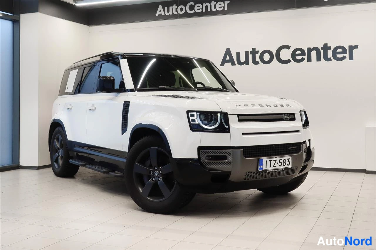 Etuviisto, nokka oikealle: Valkoinen Land Rover Defender 2022 myyjän näyttelytilassa, etukulmakuuri oikealta, rekisteritunnus.