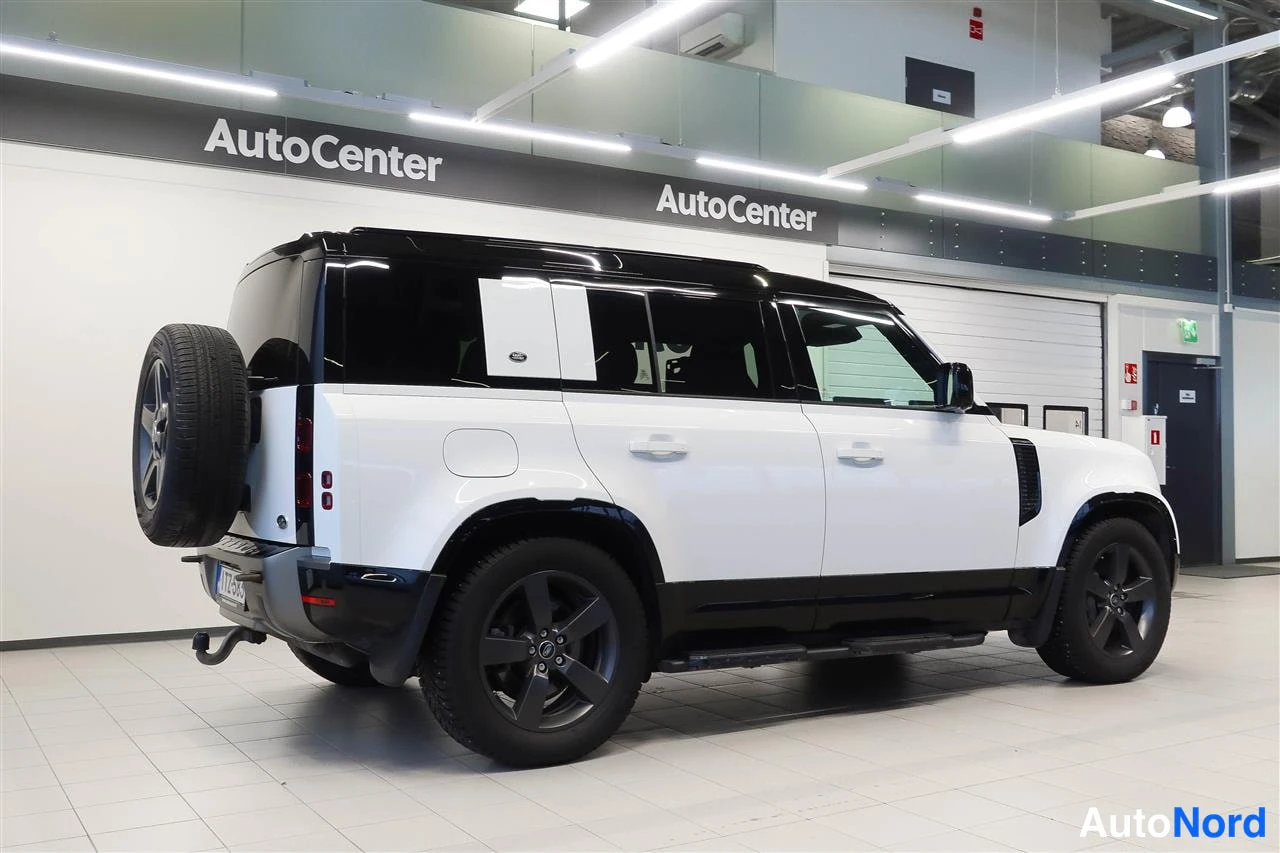 Takaviisto: Land Rover Defender 2022 takapäädystä ja vasemmasta sivusta, valkoinen kori, musta katto, reservin colta takaluukussa, mustat vanteet ja vetokoulu.