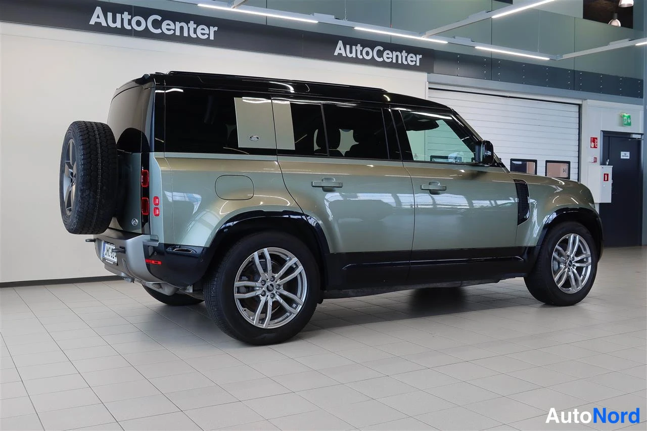 Takaviisto: Land Rover Defender 2022 takaa-lateraalista, harmaa-vihreä koritila, takarenkaita ulkopuolella.