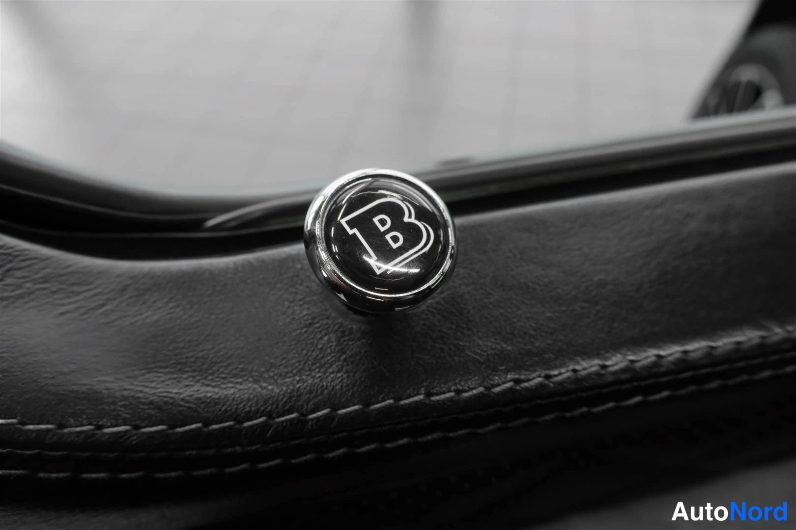 Yksityiskohta: Mustan nahkaisen pinnan BRABUS-logo halkaisijaltaan pieni pyöreä embleema.