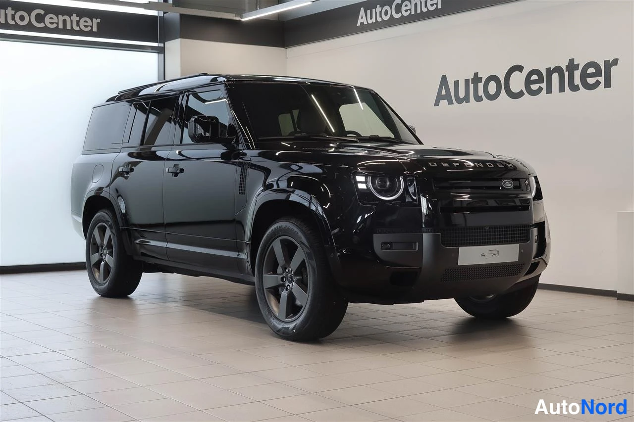 Etuviisto, nokka oikealle: Land Rover Defender 2026 musta SUV-auto AutoCenter-hallissa, kulmakuva etupää oikealla