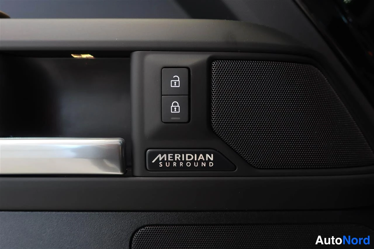 Muu: Land Rover Defenderin oven takana oleva MERIDIAN SURROUND -merkintä oven kaiutinristin vieressä ja lukitusnäppäimet, oven avaamis kahva.