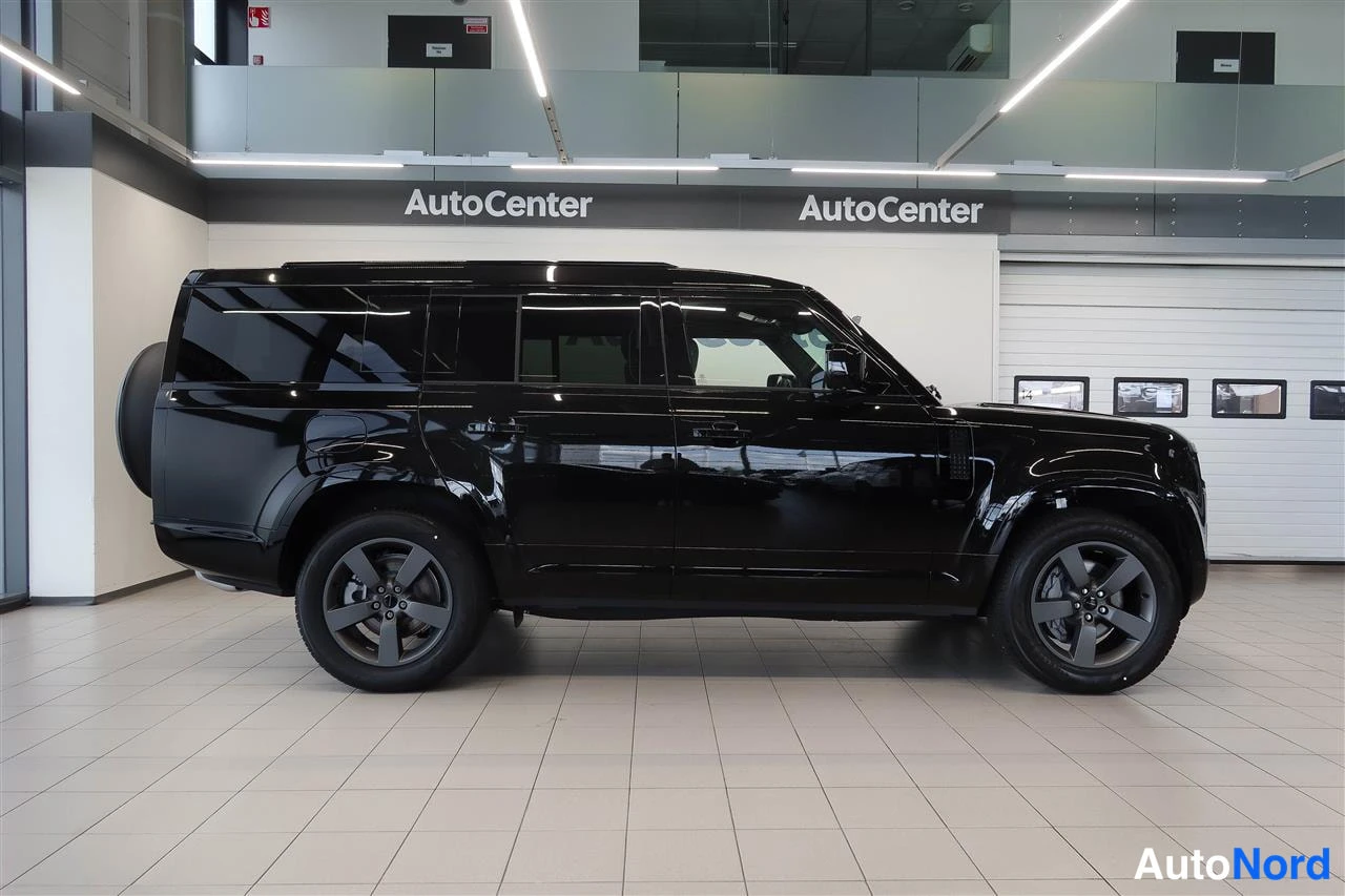 Sivulta: Land Rover Defender 2026 musta SUV sivuprofiilikuvassa AutoCenter-hallissa