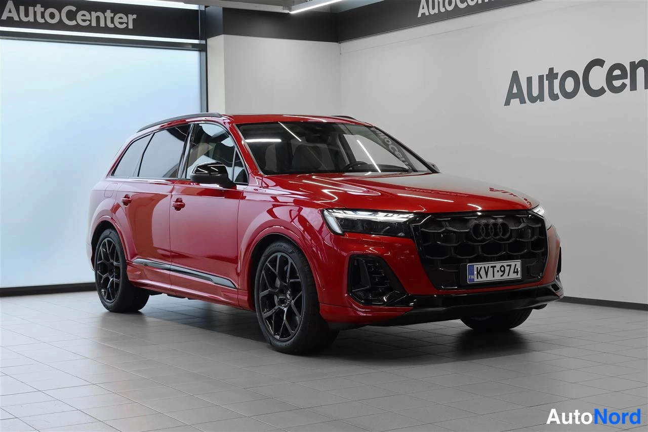 Etuviisto, nokka oikealle: Punainen Audi Q7 etu-kulmasta oikealta vasemmalla kyljellä, mustat vanteet, rekisterikilpi, AutoCenter-tausta.